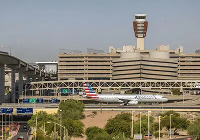 An American Airlines plane taxiing at an airport with terminal and control tower in the background.