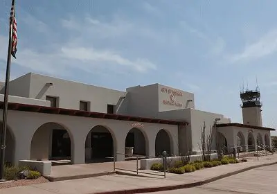 Building with arched windows and an outdoor patio under a partly cloudy sky.