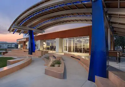 Modern outdoor seating area with blue pillars and curved roof structure.
