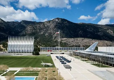 Modern architectural buildings with mountains in the background under a blue sky.