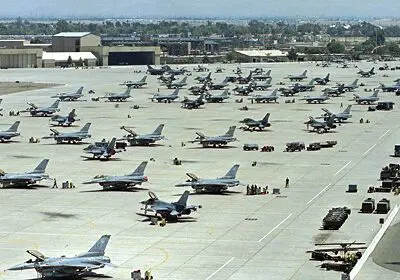 Military aircraft parked on a large airbase runway.