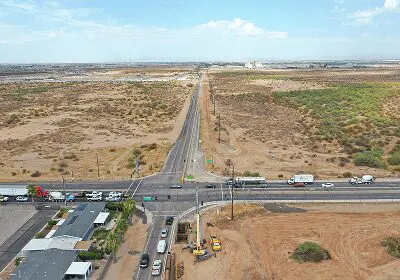 Aerial view of a rural road intersection with sparse vegetation and vehicles.