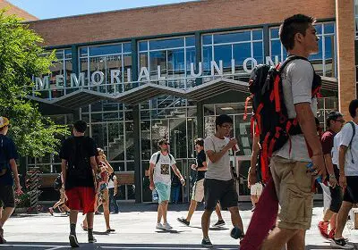 Students walking on campus near a building labeled Memorial Union.
