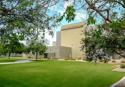 Modern building surrounded by green lawn and trees under a blue sky.