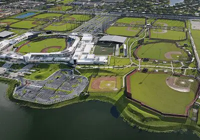 Aerial view of a large sports complex with multiple baseball fields next to a waterfront.