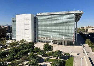 Modern building with glass facade and surrounding greenery under a clear blue sky.