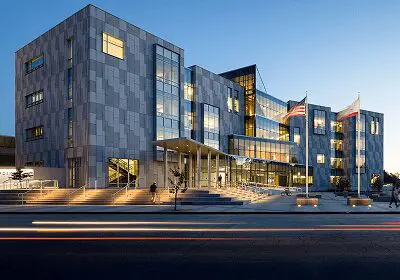 Modern glass-fronted building at dusk with illuminated interior.