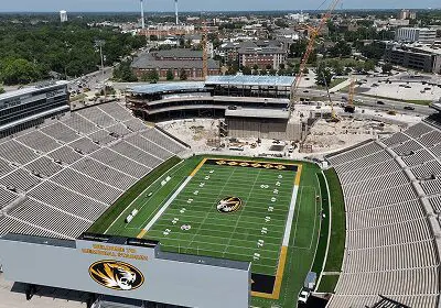 A football stadium under construction with a green field and empty stands.