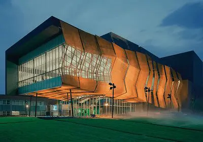 Modern building with a striking orange facade at dusk.