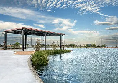A scenic lakeside park with a covered pavilion and greenery under a blue sky.