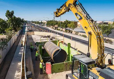 Large pipe being installed in a construction site with heavy machinery.