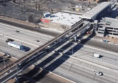 Aerial view of a highway interchange with cars and elevated train tracks.