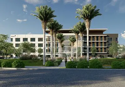 Modern building with palm trees and a clear sky.