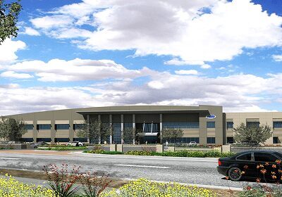 Modern corporate office building with landscaped surroundings under a partly cloudy sky.