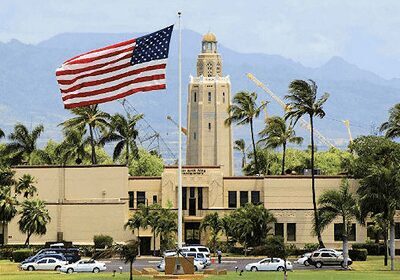 American flag flying in front of a historic building with a tower.