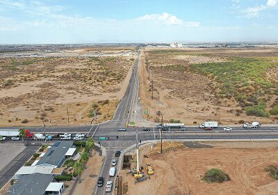 Aerial view of a rural road intersection with sparse vegetation and vehicles.