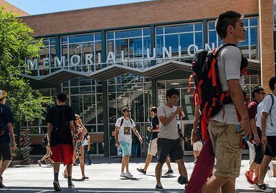 Students walking on campus near a building labeled Memorial Union.