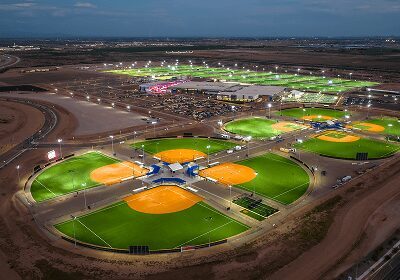 Aerial view of a brightly lit softball complex at dusk.
