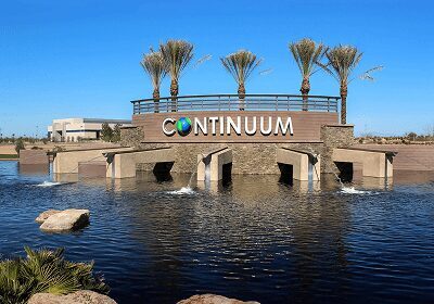 Modern building with palm trees and a water feature under a clear blue sky.