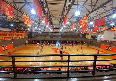 Indoor basketball game in a gymnasium with spectators.