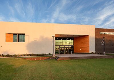 Modern building entrance with glass doors and a lawn in front.