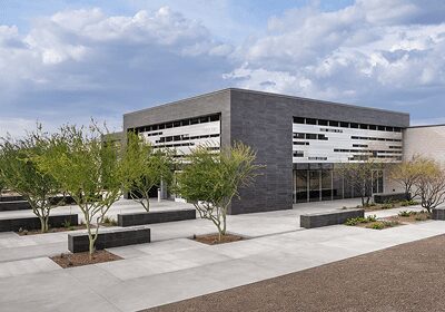 Modern building with clean lines and surrounding greenery under a cloudy sky.