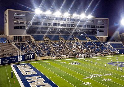 A brightly lit football stadium with fans seated in the stands.