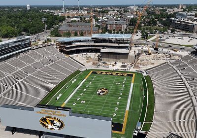 A football stadium under construction with a green field and empty stands.