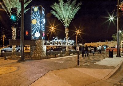 Night scene of Tolleson entrance with illuminated sign and palm trees.