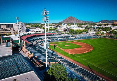A bright, empty baseball stadium with a mountain in the background.