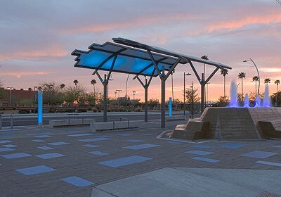 Modern pavilion at sunset with clear sky and palm trees.