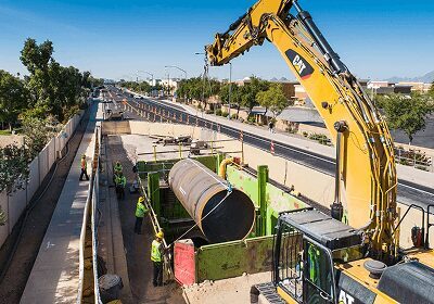 Large pipe being installed in a construction site with heavy machinery.